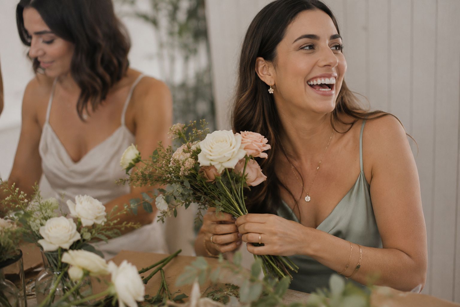 A guest laughing while holding her half-finished bouquet at a Florenne & Co. workshop table